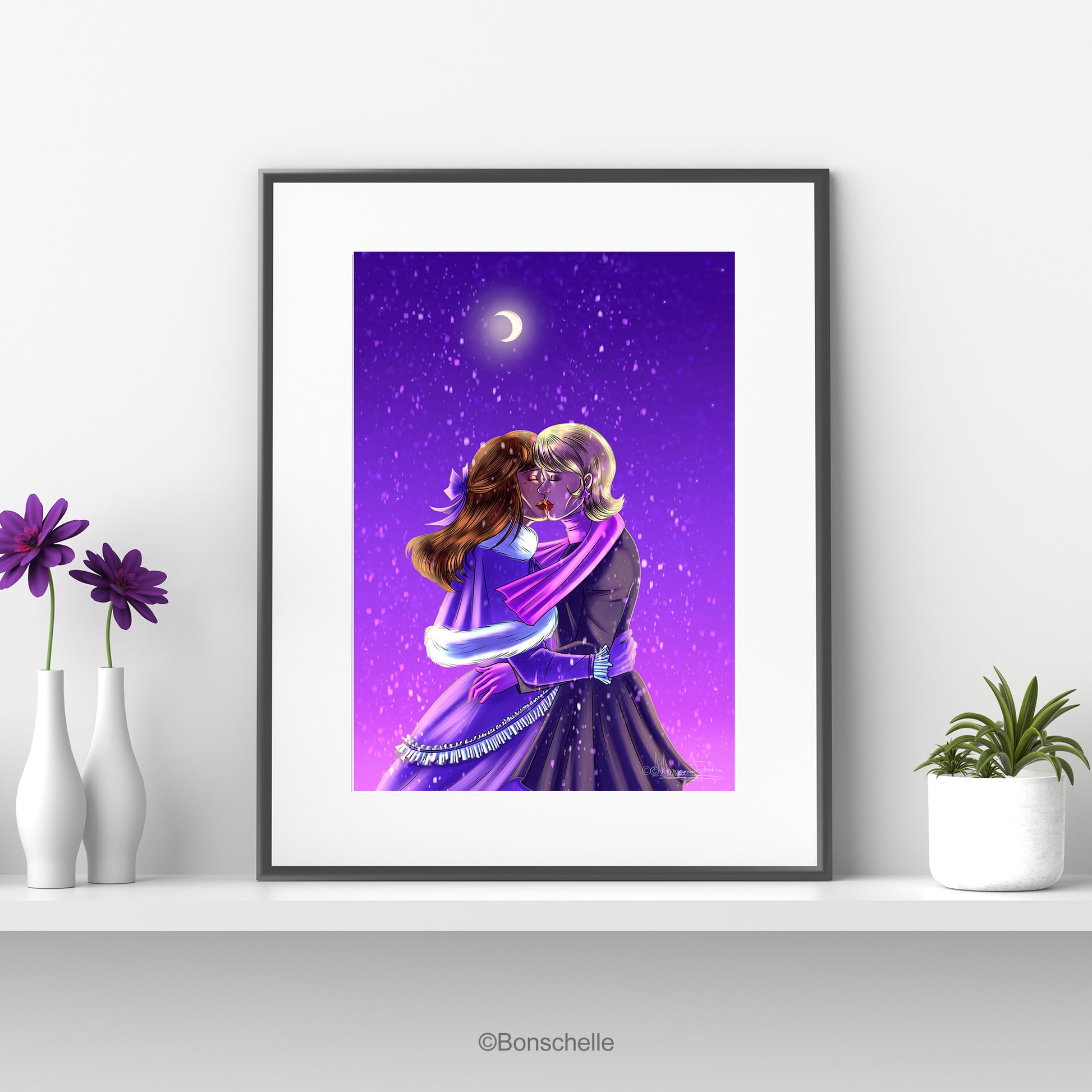 An original art print showing two young woman sharing a kiss in the snow against a purple night sky. A crescent moon is overhead.  The print is mounted on a white surround and framed in black. It sits on a white shelf. One one side are flower vases, on the other a flower pot with a cactus.