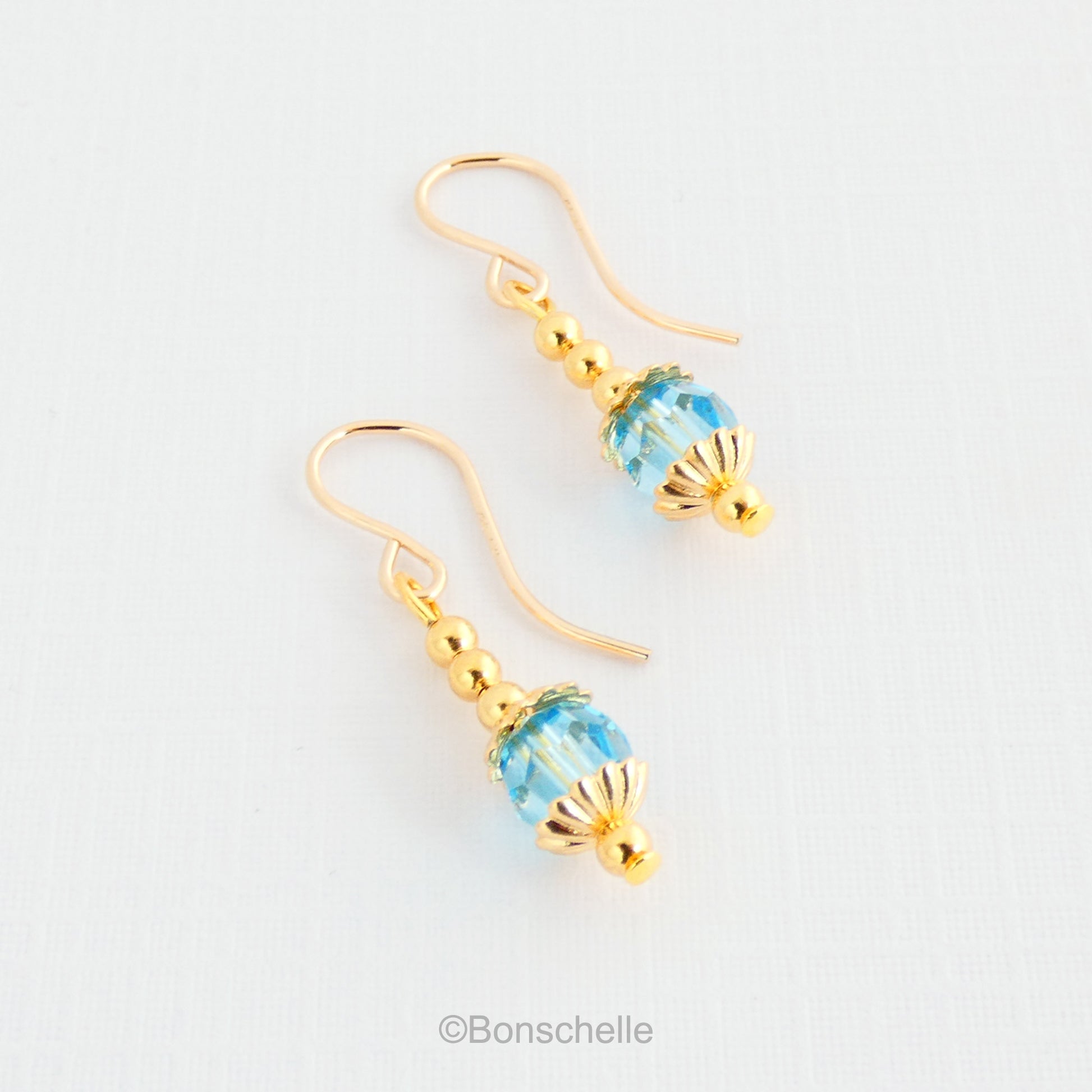 Handmade dangle earrings made with turquoise coloured Swarovski cut glass crystal faceted beads, small gold toned beads and 14K gold filled earwires.