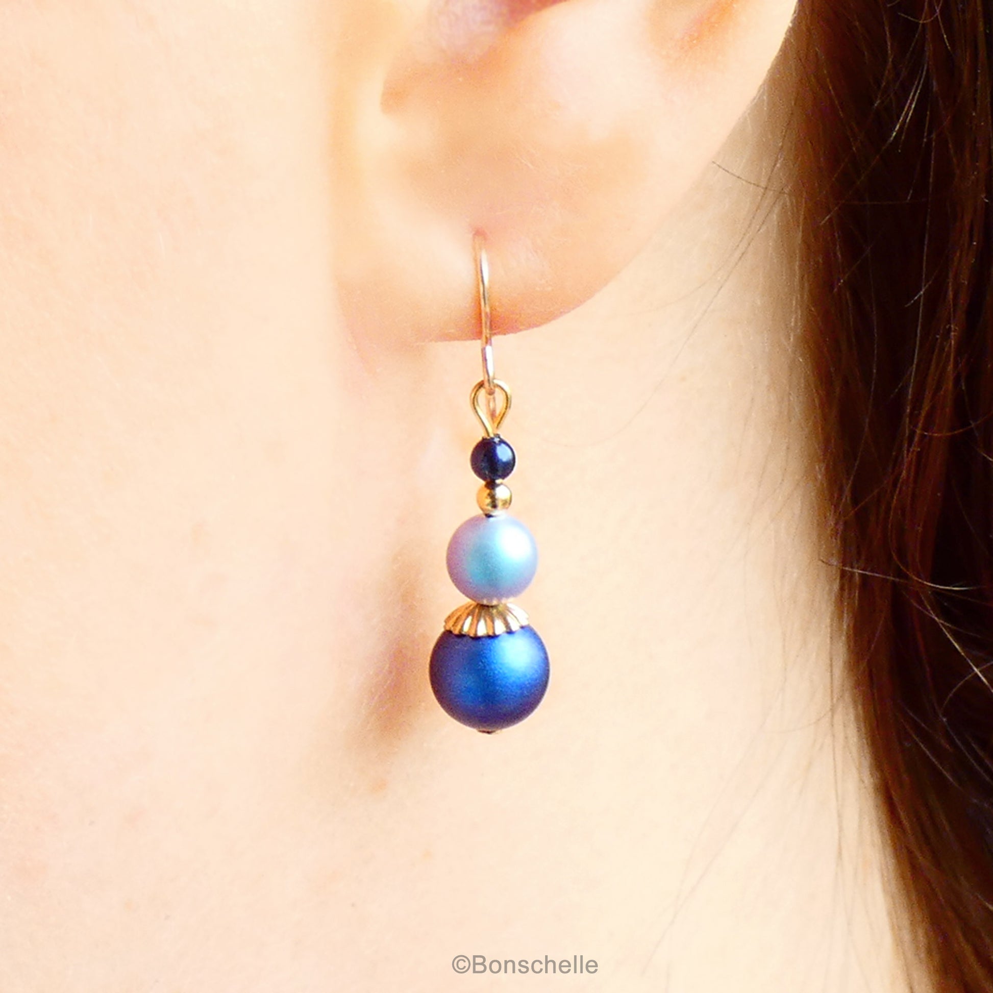 Blue swarovski crystal pearl beaded drop earrings with 14K gold filled earwires for women with gold accents shown worn on an ear