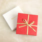 Image of a box wrapped with Bonschelle red tissue and gold bow 