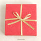 Image of a box wrapped with Bonschelle red tissue and gold bow 
