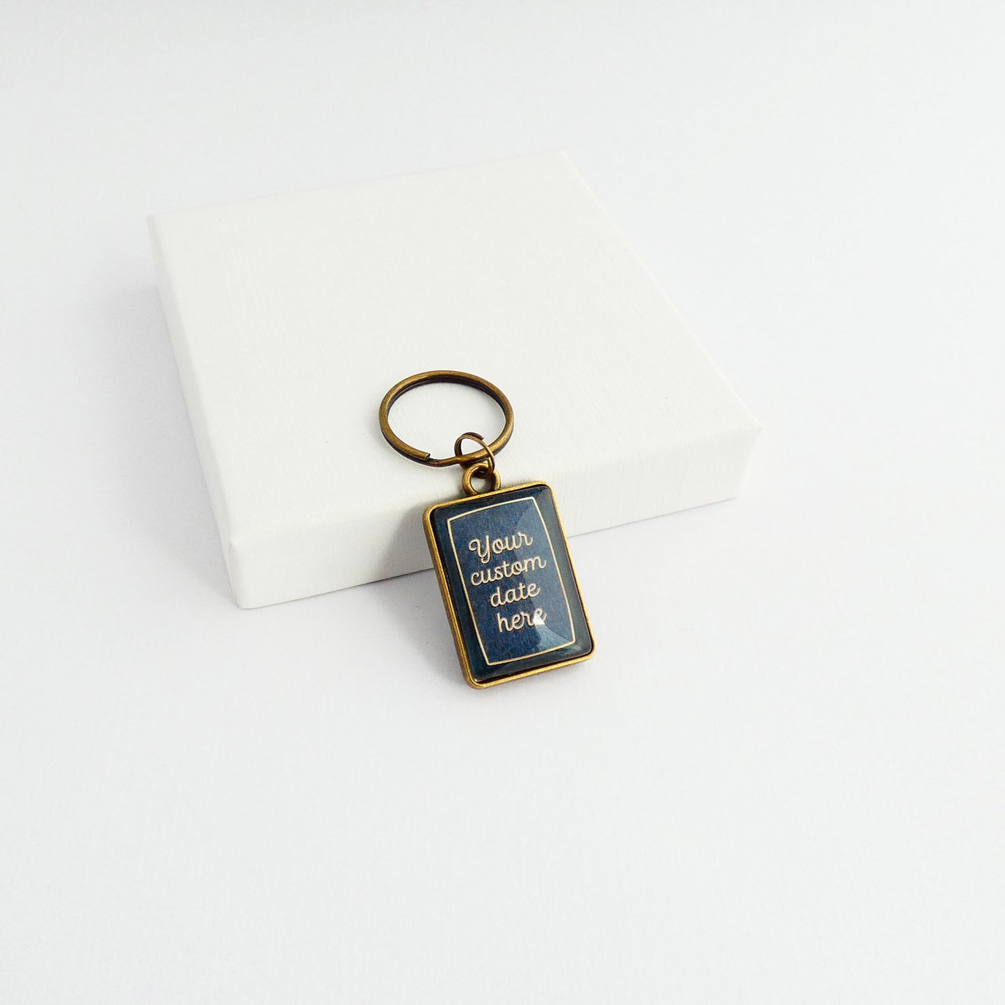 A double sided bronze and navy blue rectangle keyrings showing the back side with words 'Your custom date here'