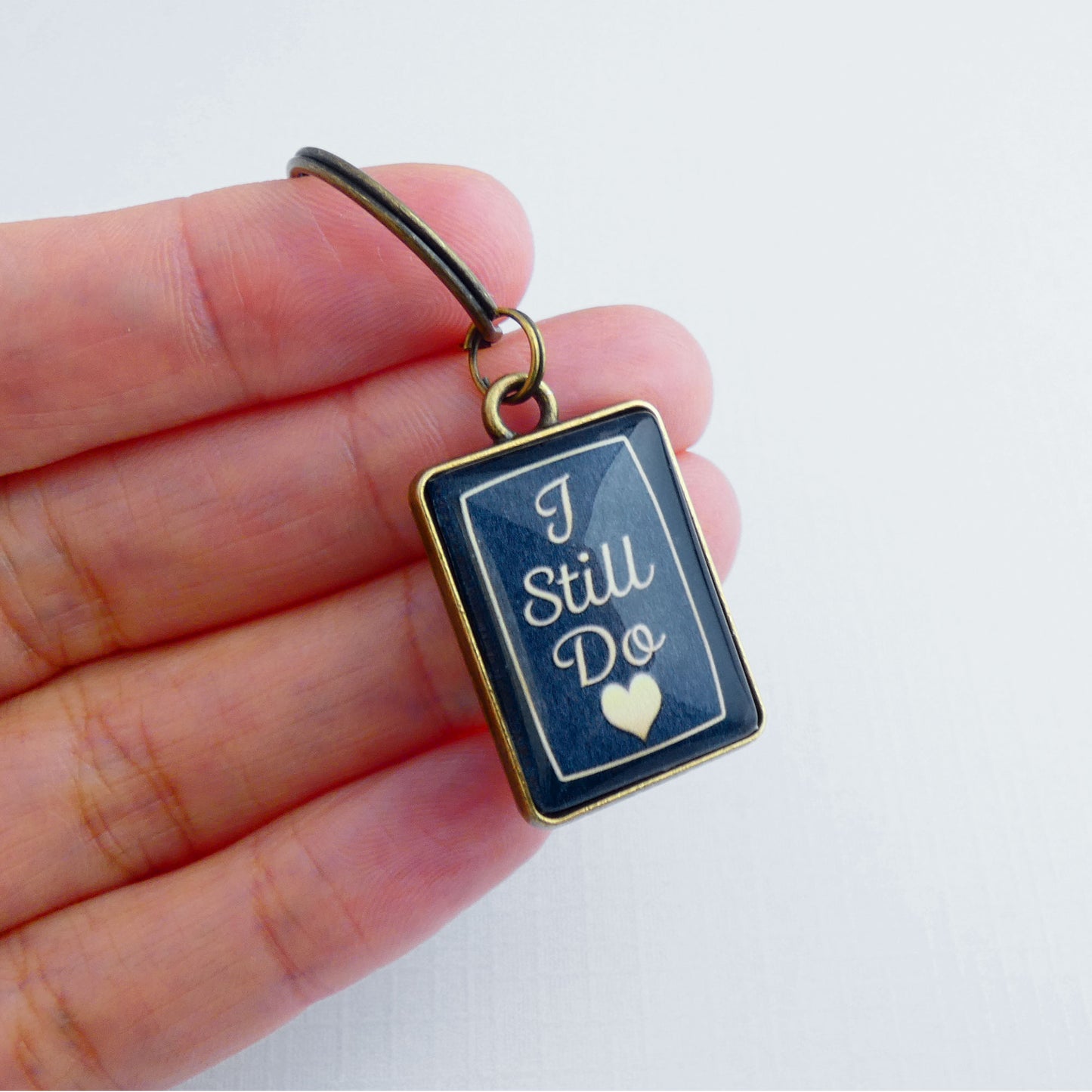 A double sided bronze and navy blue rectangle keyrings showing the front side with  the words 'I still do' 