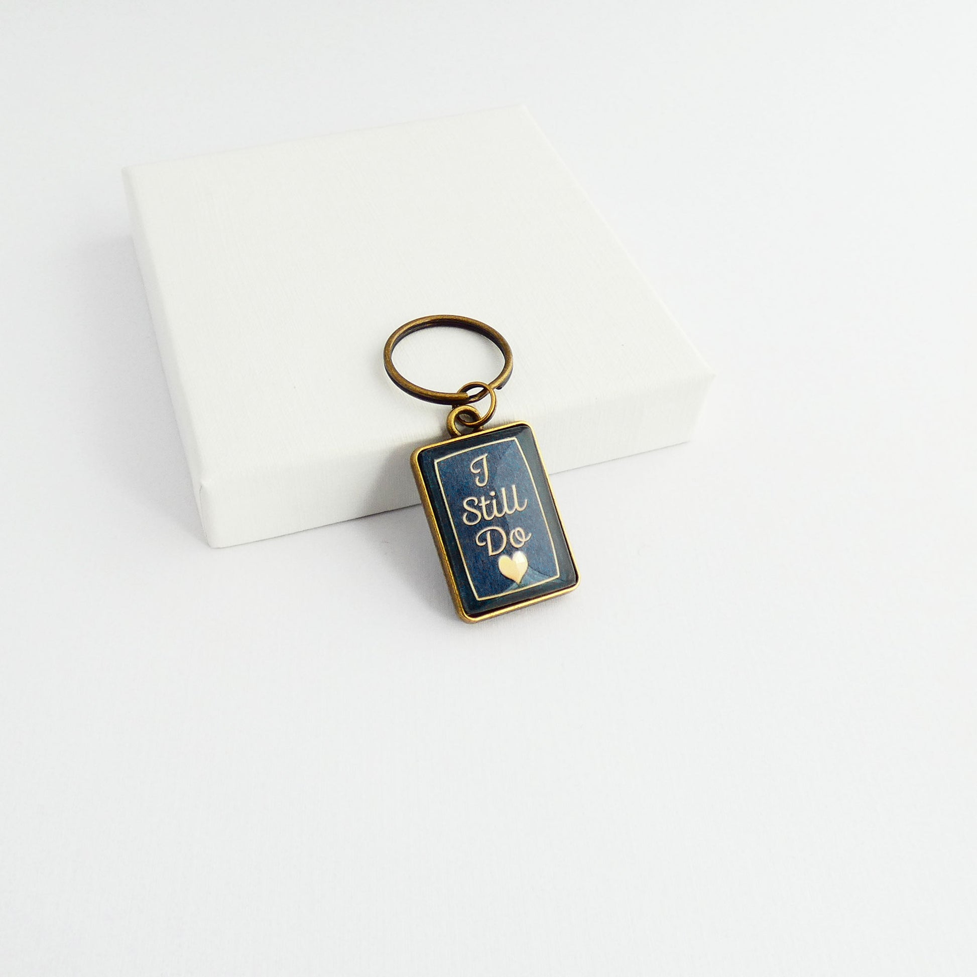 A double sided bronze and navy blue rectangle keyrings showing the front side with the words 'I still do' 