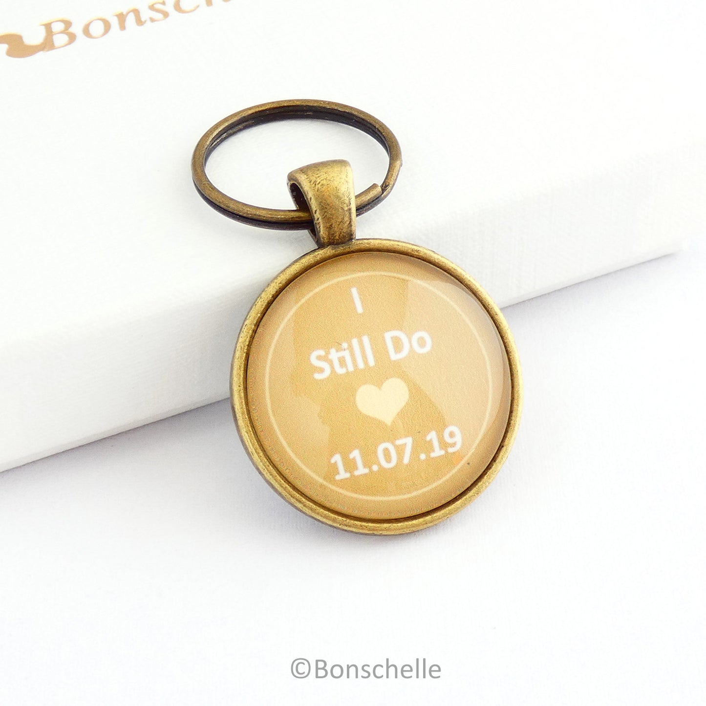 Round bronze toned wedding anniversary keyring gift with the words I still Do, a small heart and a custom date