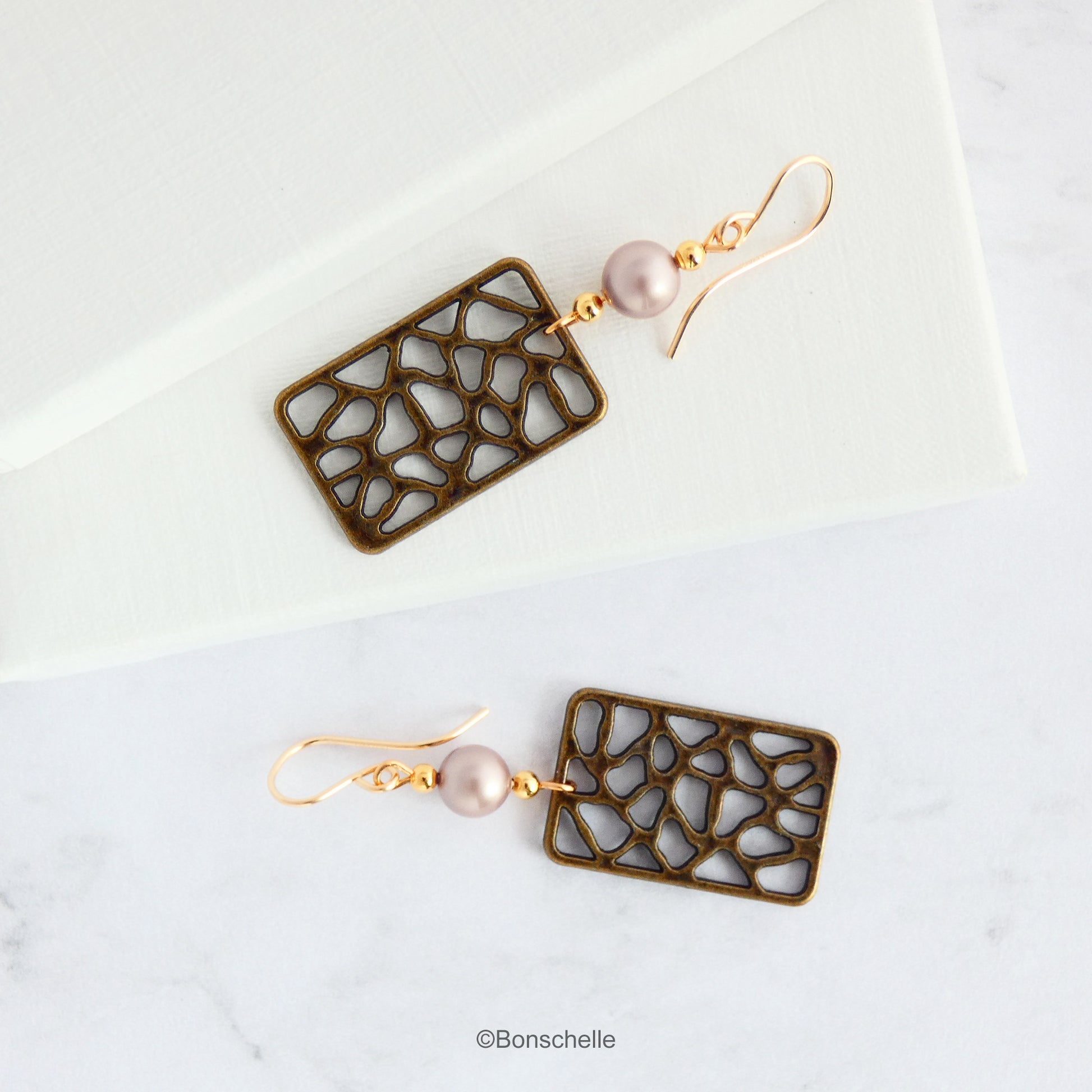 Handmade earrings made with rectangular shaped antique bronze filigree style charms, Swarovski simulated pearls in a light almond shade, gold toned beads and 14K gold filled earwires. 