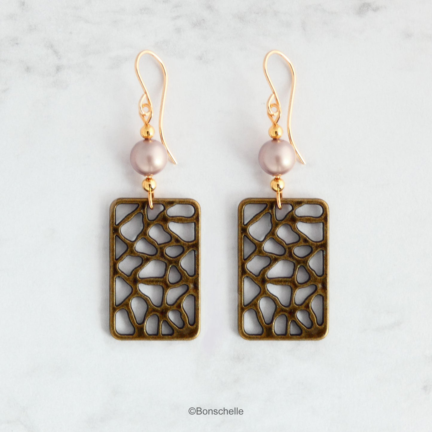 Handmade earrings made with rectangular shaped antique bronze filigree style charms, Swarovski simulated pearls in a light almond shade, gold toned beads and 14K gold filled earwires. 