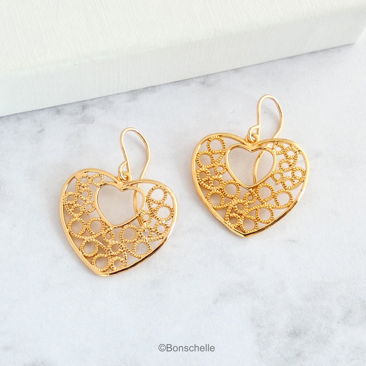 18K gold plated filigree heart earrings with 14K gold filled earwires shown on a surface