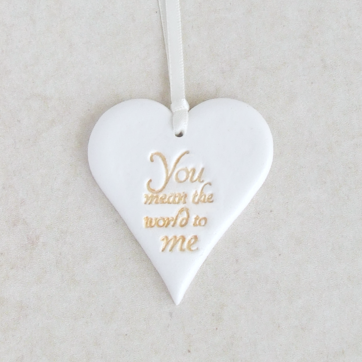 Heart shaped hanging ornament made from white clay with gold worlds 'You mean the world to me' 