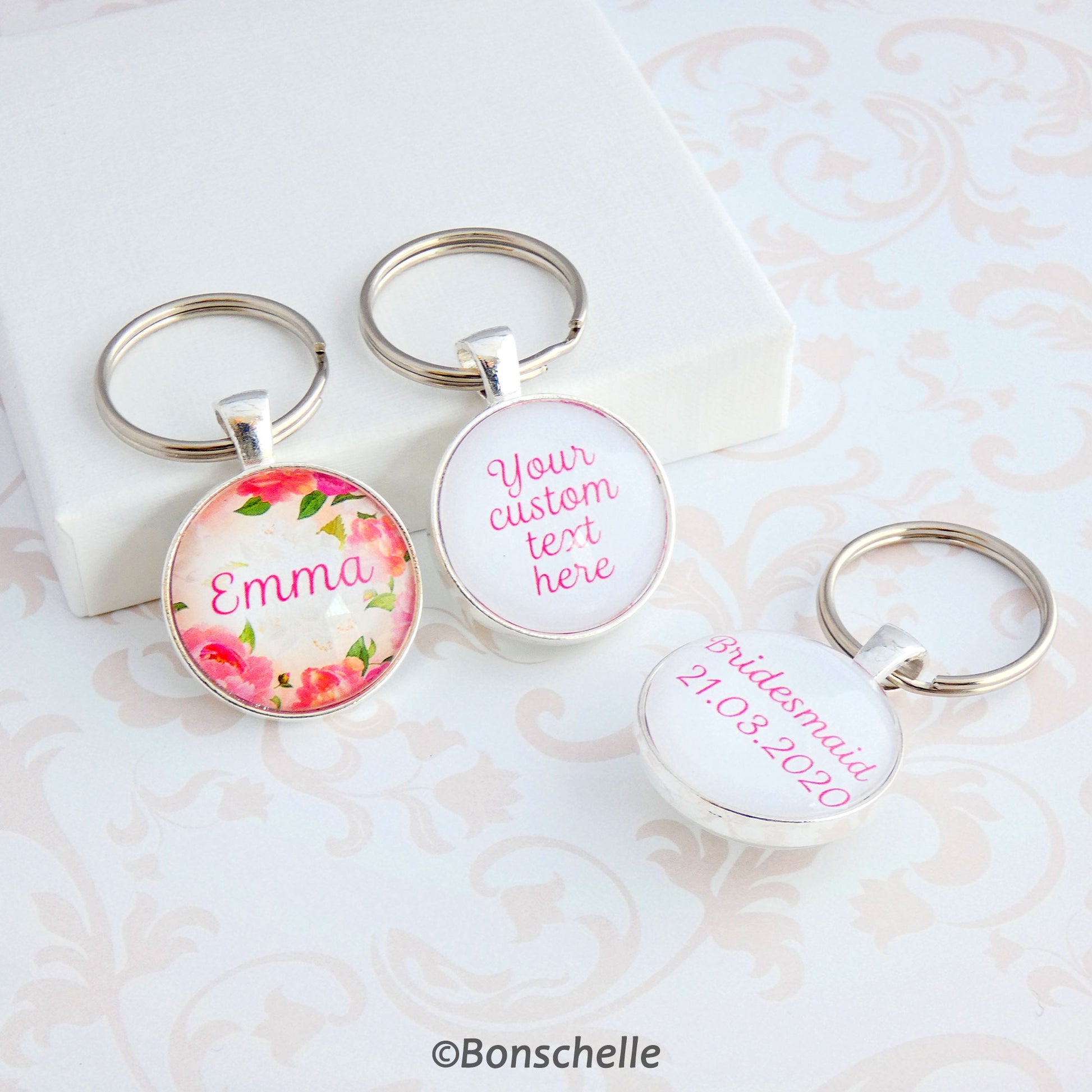Double sided silver toned round keyring with a name and floral design on the front and your custom text on the back showing an additonal example of text on the back.