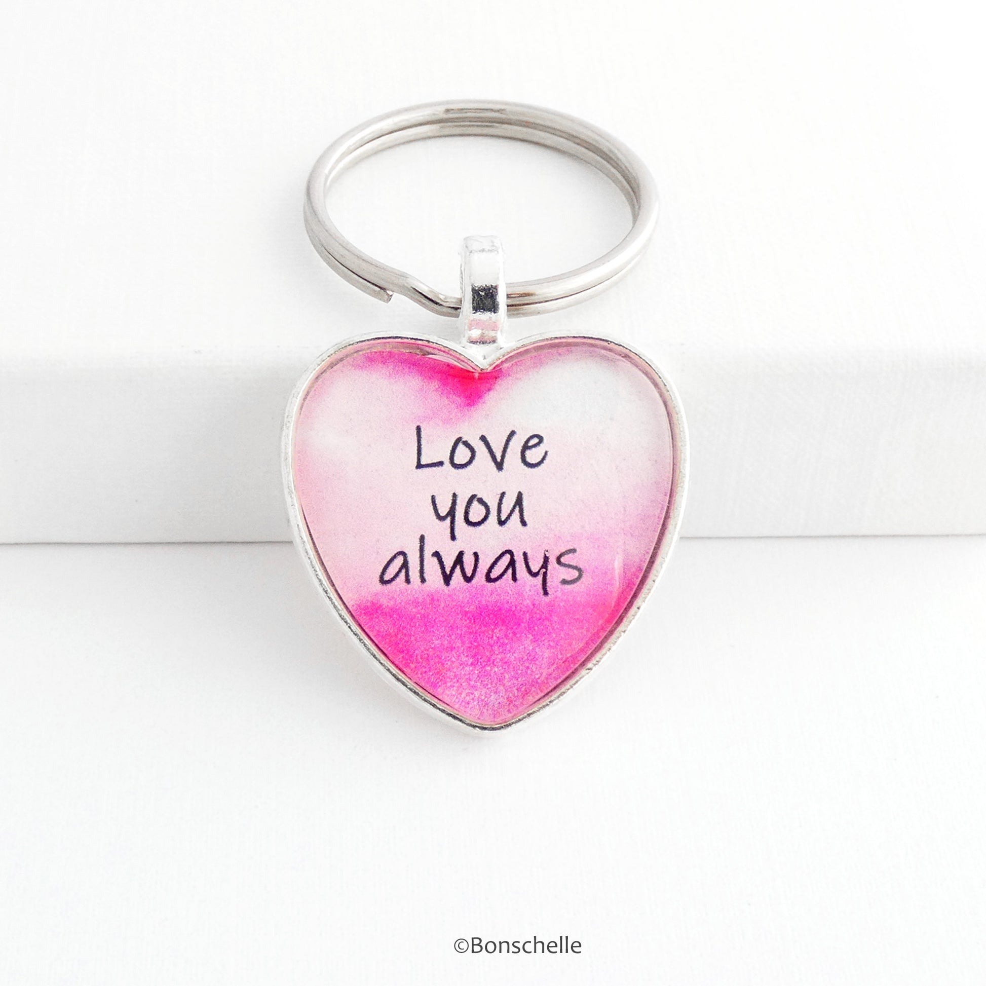 Silver toned heart shaped metal keyring with pink and white design and the worlds 'Love you Always' capped with a clear glass cabochon