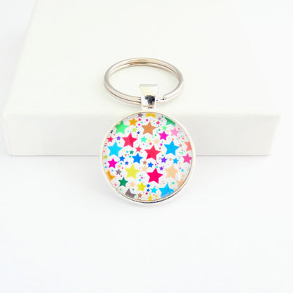 A round shaped silver toned metal keyring with a colourful star pattern design capped wtih a clear glass cabochon