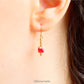 Drop earrings with a single bright red Swarovksi crystal beads, 3 smaller gold toned metal beads and 14K gold filled earwires shown being worn.