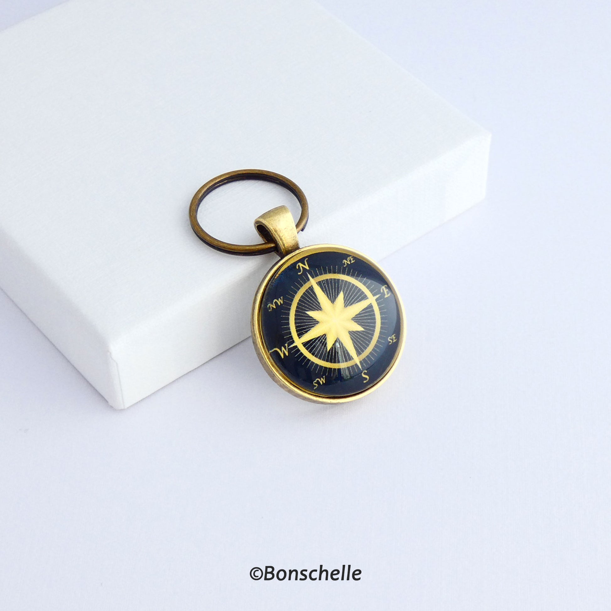 Front  view of a personalised bronze metal round double sided keyring, with light bronze coloured compass rose on the front against a navy blue background 